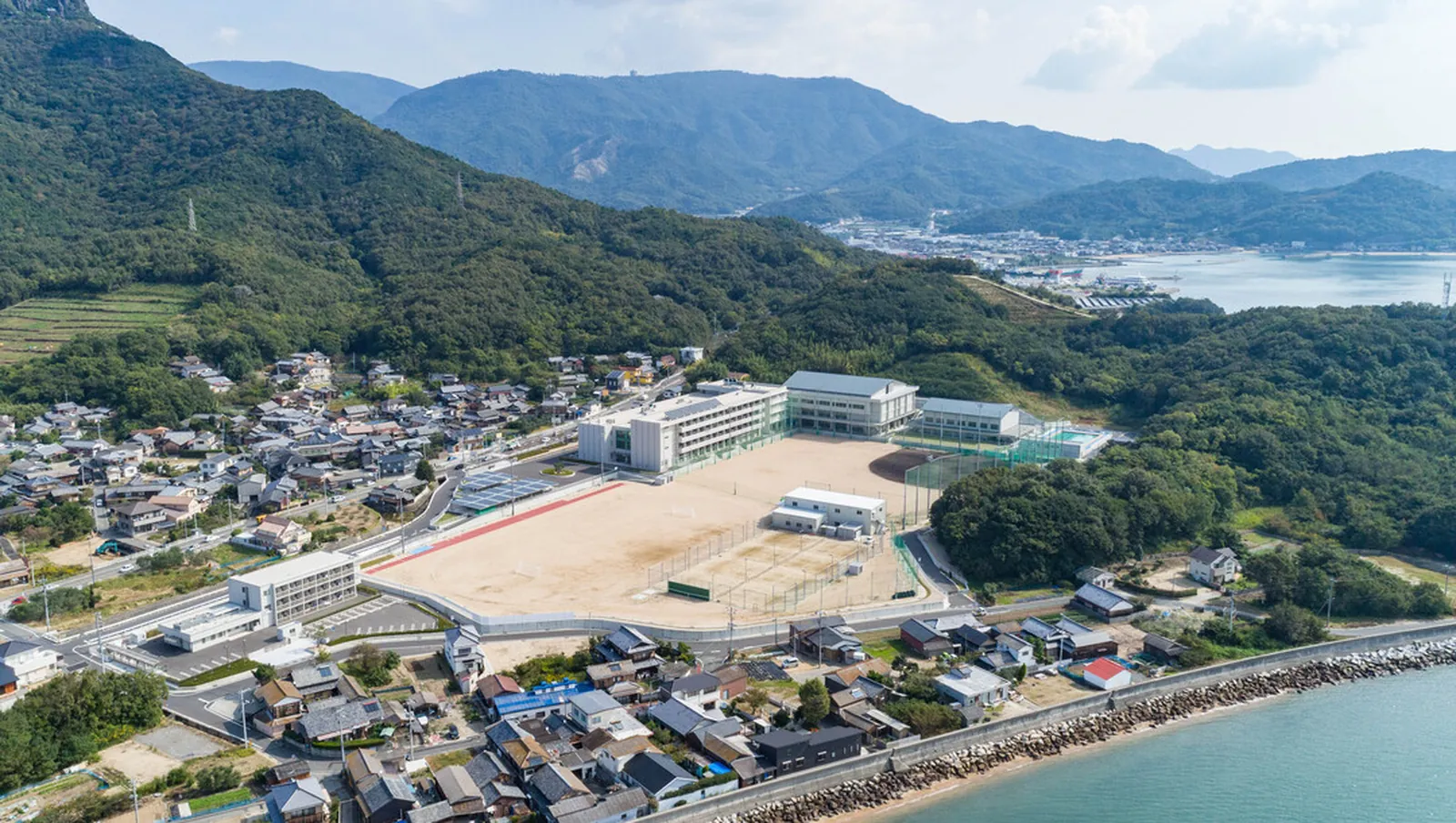 海沿いの高校のグラウンドと校舎を上空から撮影した写真