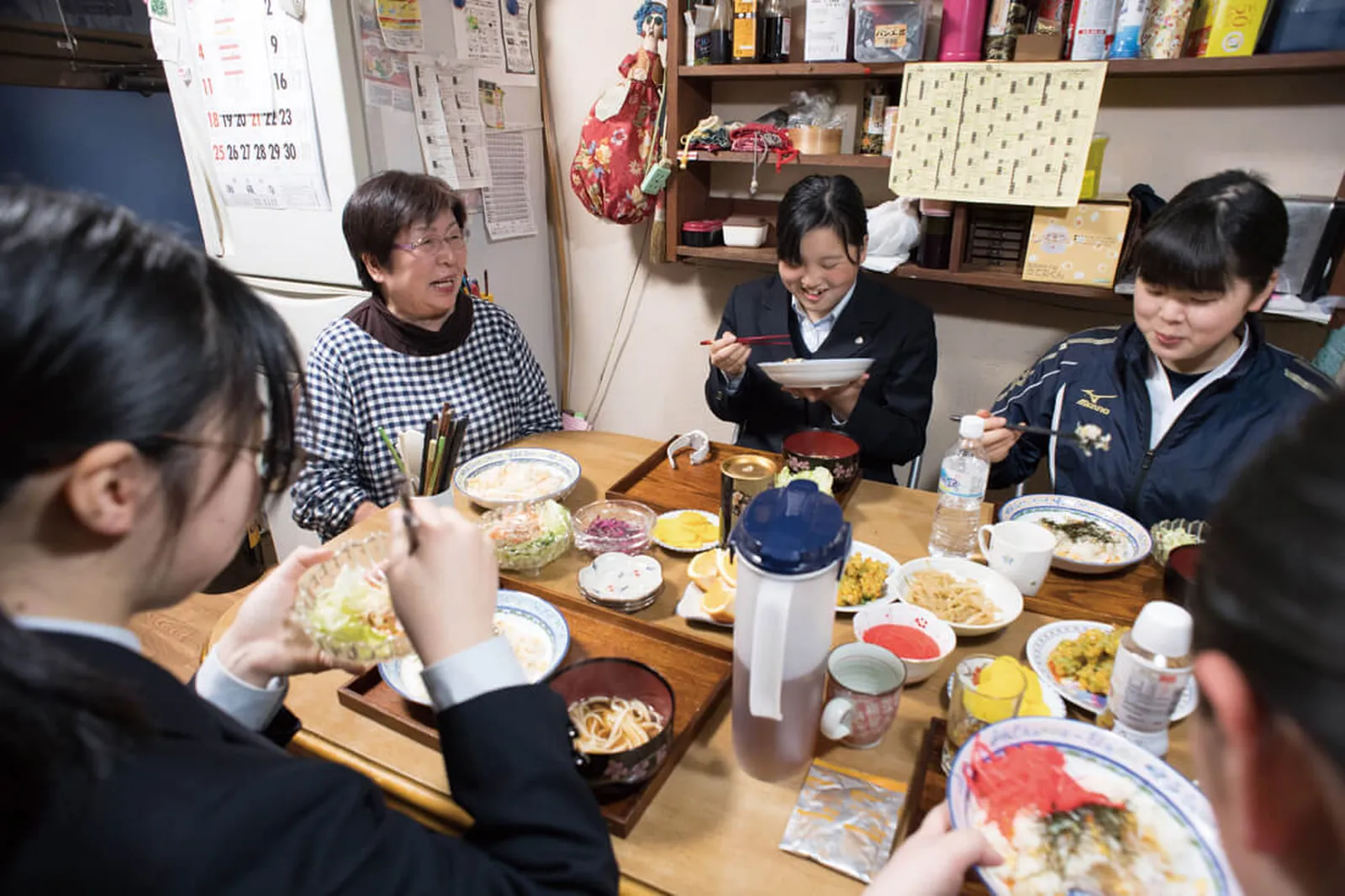 下宿先の食卓を家族や生徒たちで囲んでいる写真